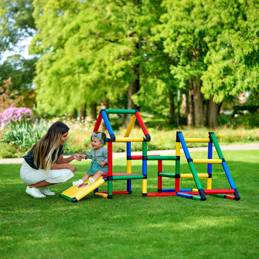 Mama hält die Hand ihres Babys auf der Rampe des QUADRO Kletterparkour Classic im Garten