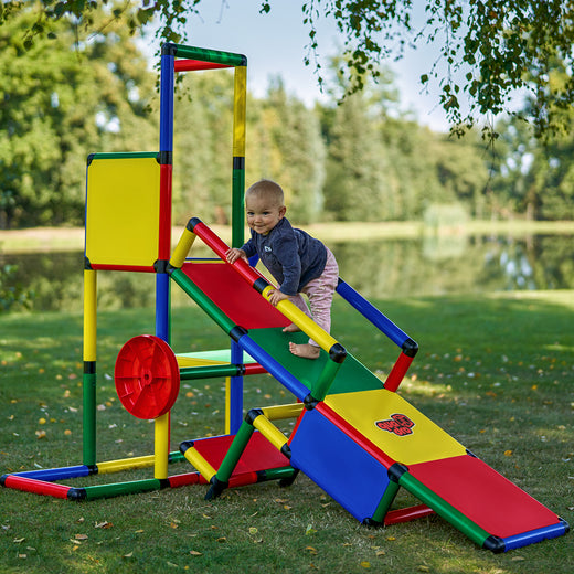 Kleinkind klettert über die Rampe zum Spielturm des QUADRO Evolution Classic, Multirad links