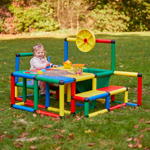 Kleinkind spielt am Sandtisch des QUADRO Möbel Kit L Classic mit Sitzbank im Garten