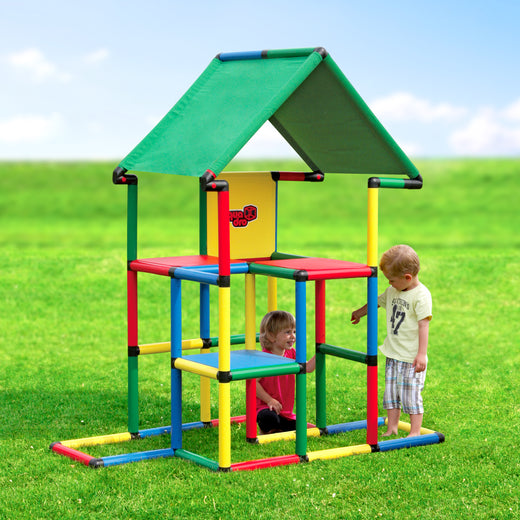 Zwei Kinder spielen am QUADRO Junior Classic mit zweistöckigem Spielturm und grünem Dachtextil im Garten