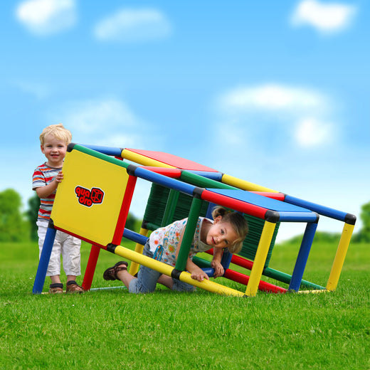 Zwei Kinder erkunden den QUADRO Starter Classic im Garten, eines krabbelt durch den geneigten Aufbau